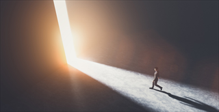 person walking toward a slice of light 