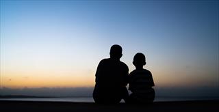 adult and child sitting and watching the horizon