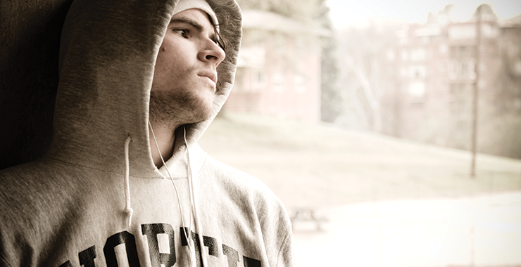 College student with a hoodie and headphones looking troubled