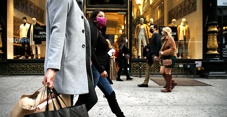 people walking on a city sidewalk in front of clothing storefront