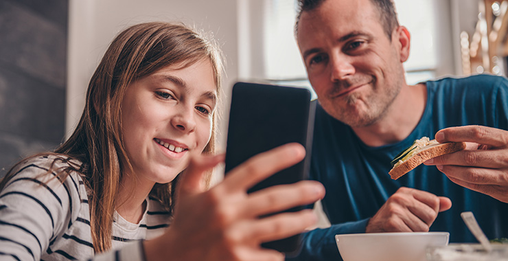 teen showing her father something on her smartphone