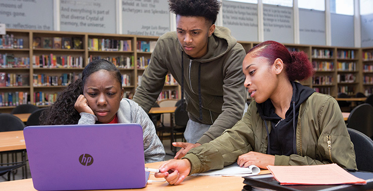 students having a conversation in front of a laptop