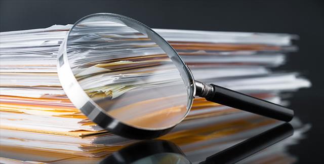 magnifying glass propped up against stack of journal articles