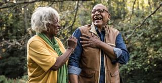 older Black couple walking and laughing in park