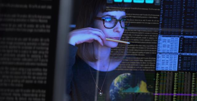 Woman holding a pencil staring at computer screen