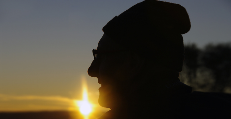 older man silhouetted against sunrise