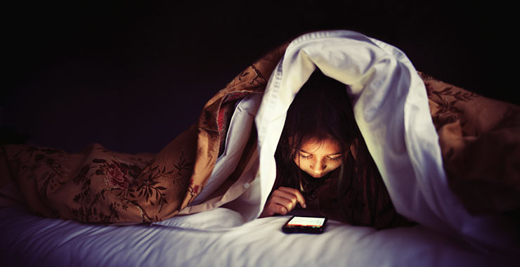 teen girl scrolling through social media while in bed