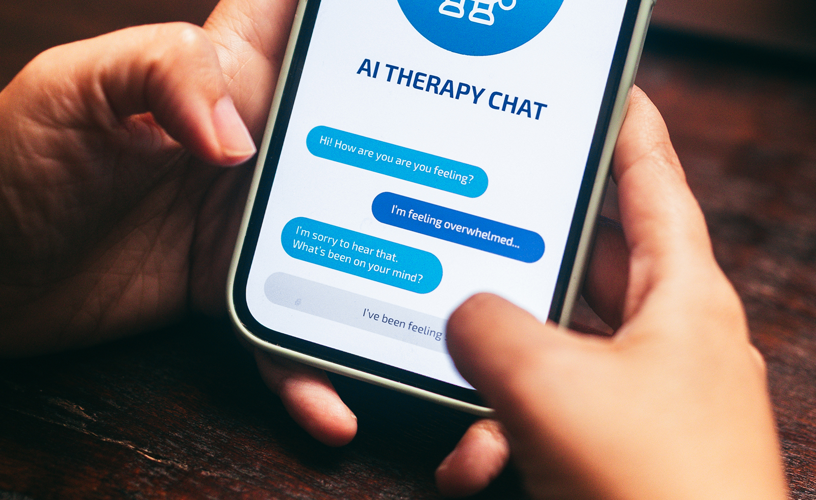 Hands holding a smart phone with “AI Therapy Chat” app displayed on screen.
