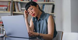 woman with a confused expression looking at a laptop screen 