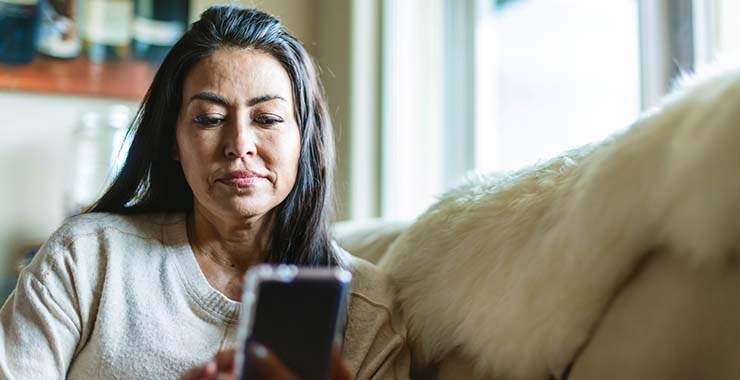 woman sitting on a couch looking at her smartphone