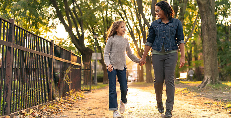 Girl and mother walking through a park