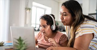 Young girl with autism participates in an online research study assisted by her mother.