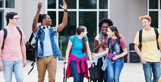 Young girl using crutches walks alongside diverse group of friends.