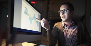 person pointing at something on a computer monitor