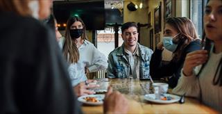 Friends out at dinner with some wearing masks and some not