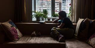 Person home alone gazing out of window