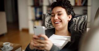 Woman looking at cell phone while laughing