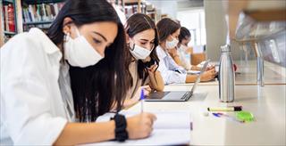 Students in masks studying individually in library