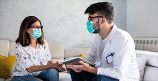 Doctor and patient sitting down wearing face masks