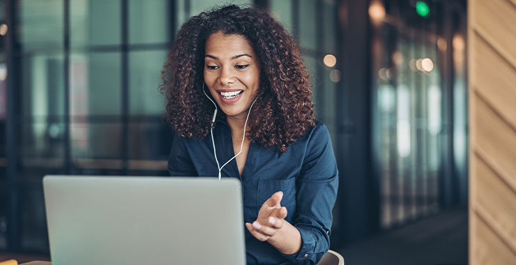 Woman with earphones smiling in front of laptop
